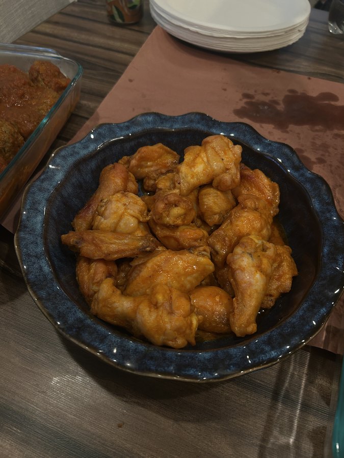Baked wings tossed in buffalo sauce, piled in a blue bowl